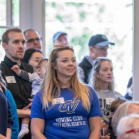 GVSU Alumni sitting and standing in the Alumni House and Visitors Center at Rowing Celebration event